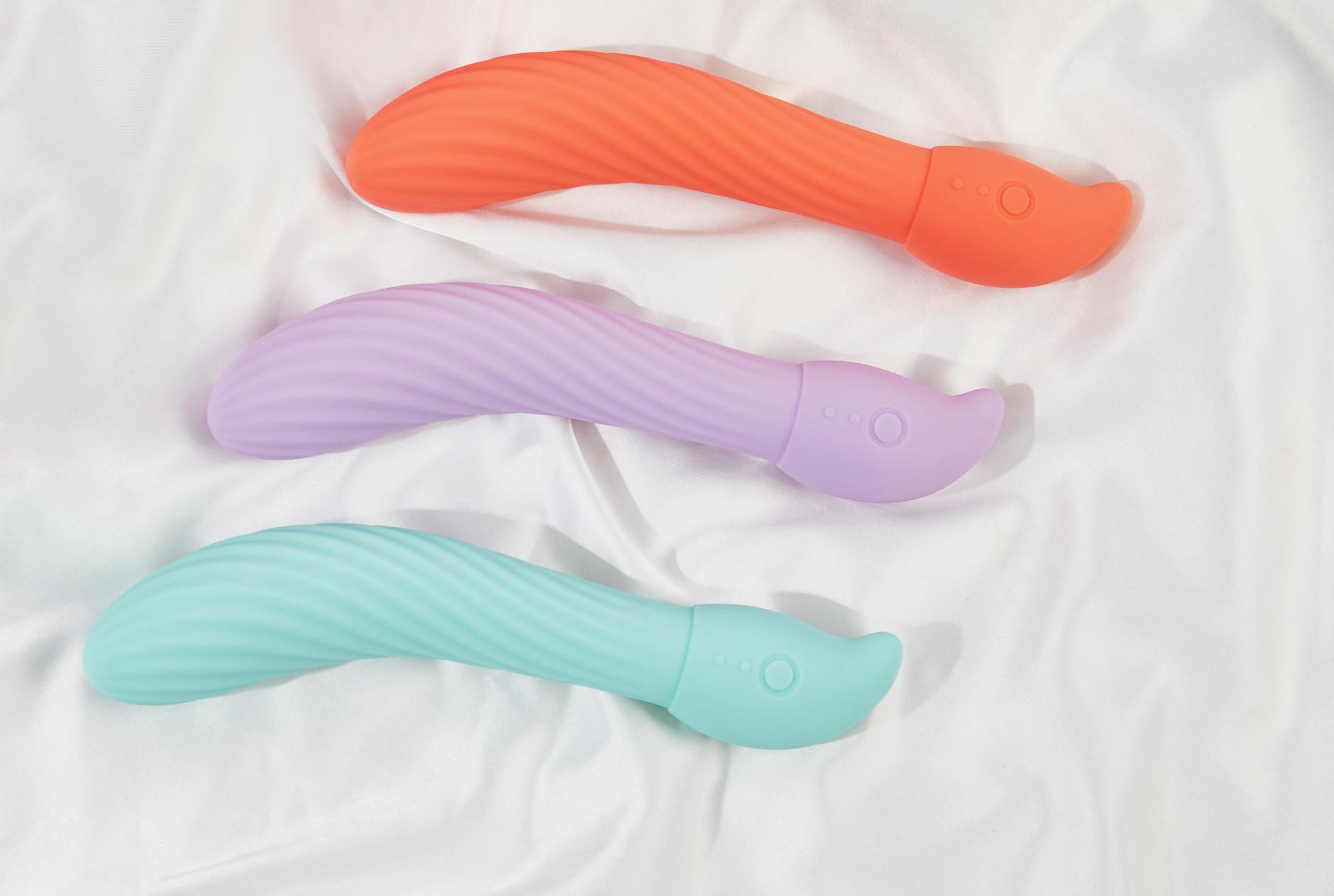 Three colorful lemon vibrators and clitoral suction toys arranged on soft white fabric