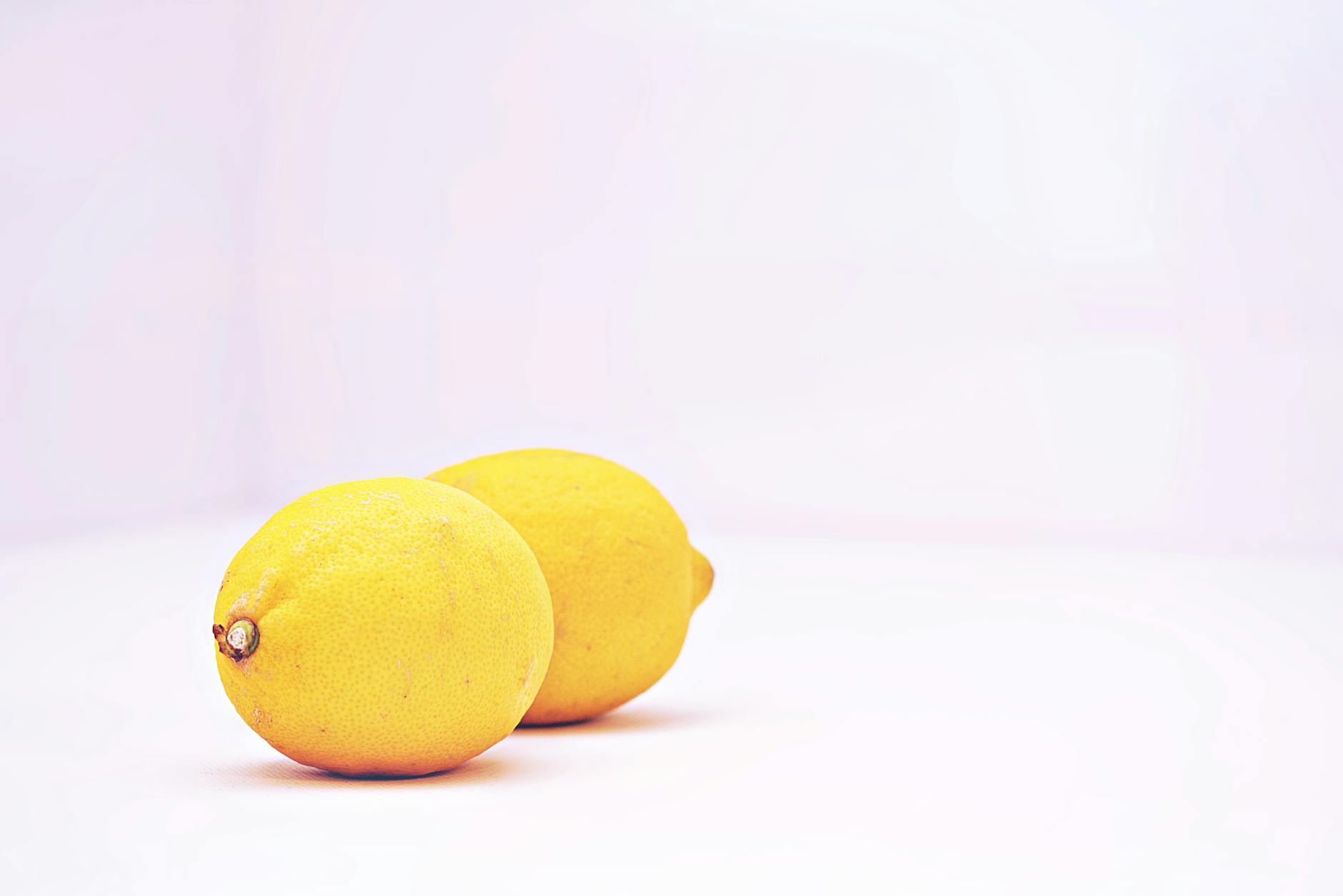 Two vibrant lemons on a clean white background, symbolizing fresh beginnings and renewed sensation