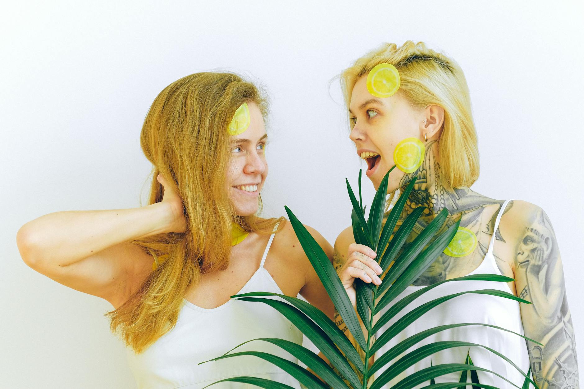 Two women smiling and enjoying fresh lemons together, expressing confidence and joy