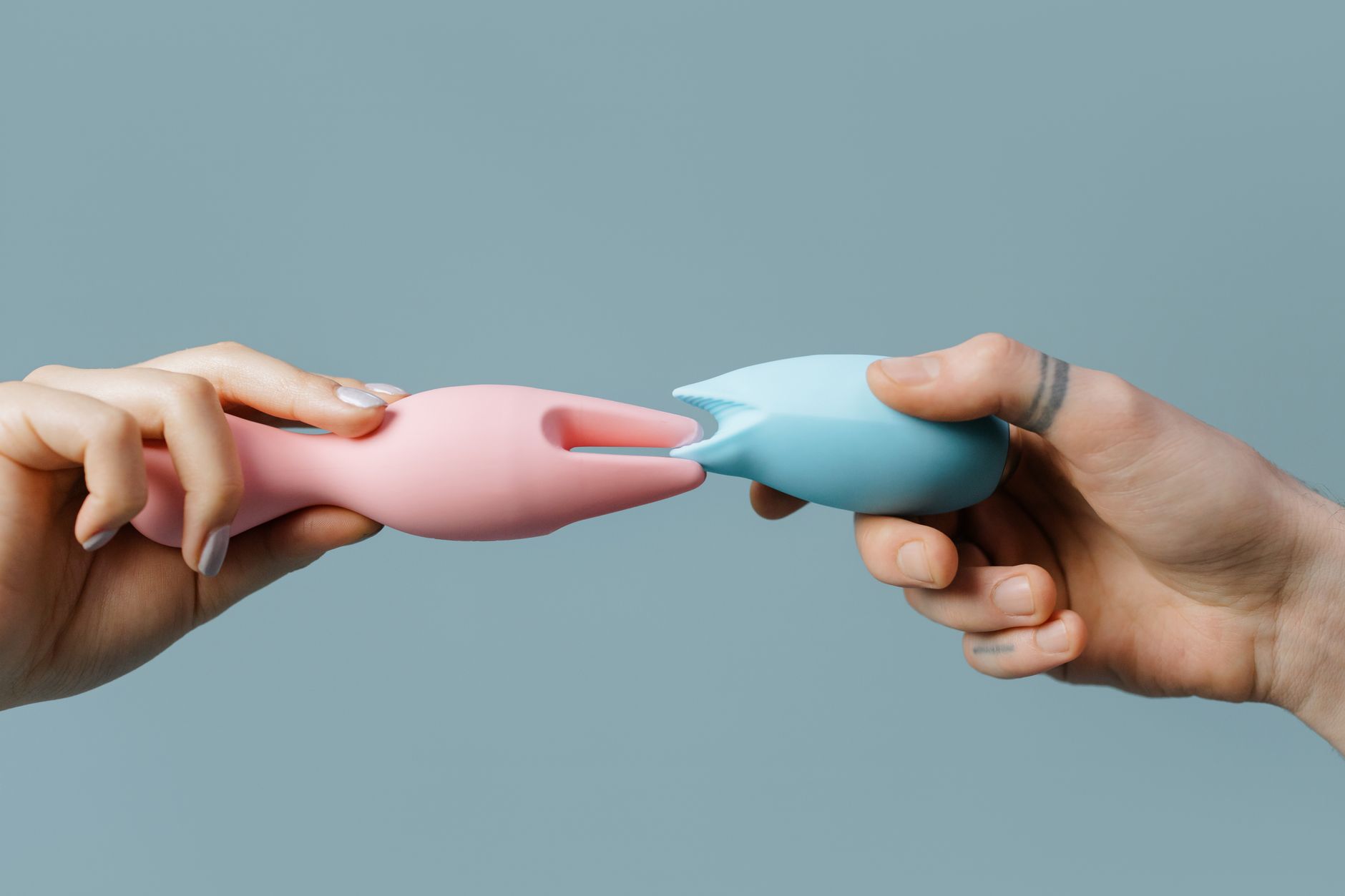 Hands holding pastel-colored silicone vibrators for comfortable exploration