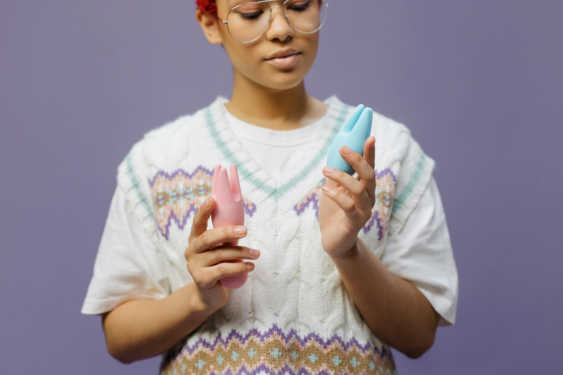 Woman holding a blue clitoral vibrator, contemplating the experience of intimate self-pleasure with a partner present.