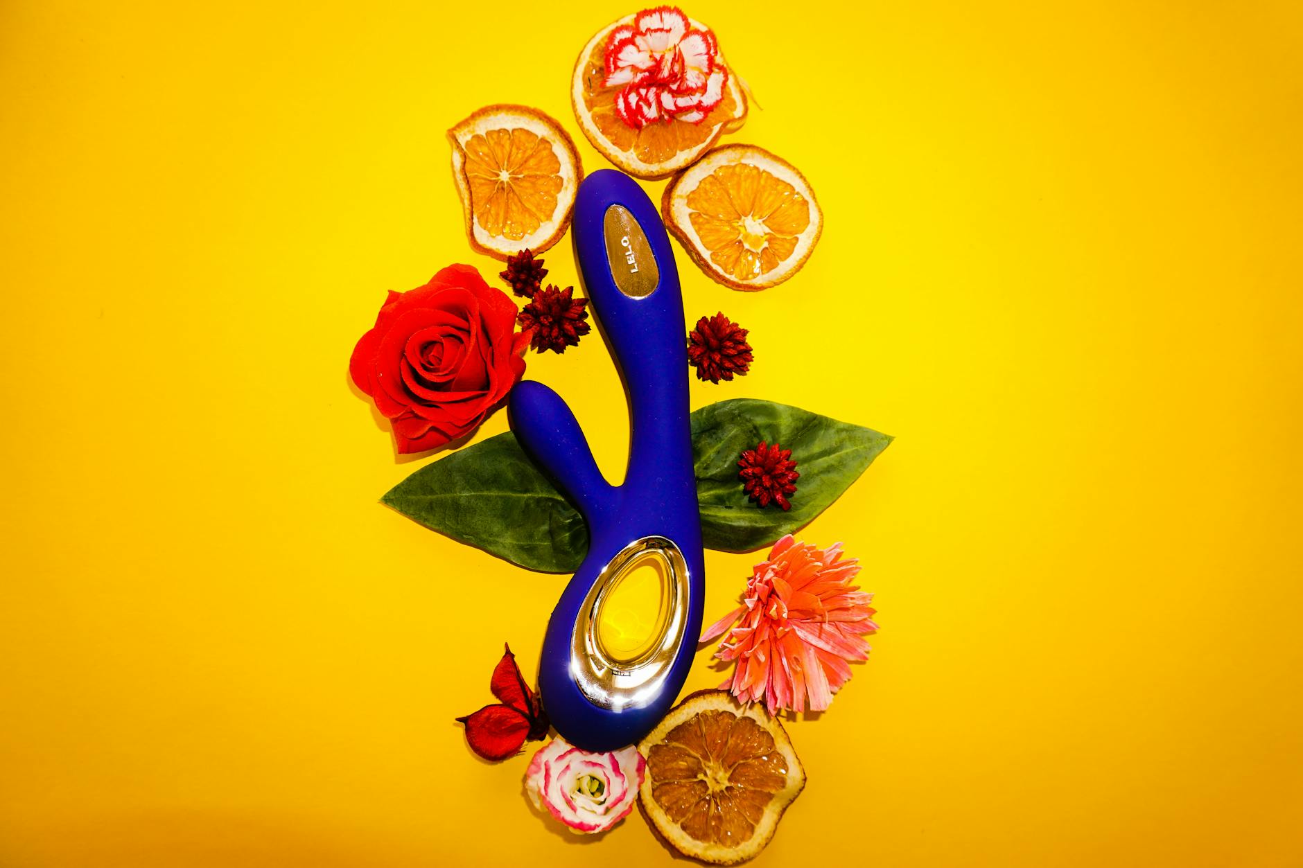 Blue lemon vibrator surrounded by flowers and citrus on warm background