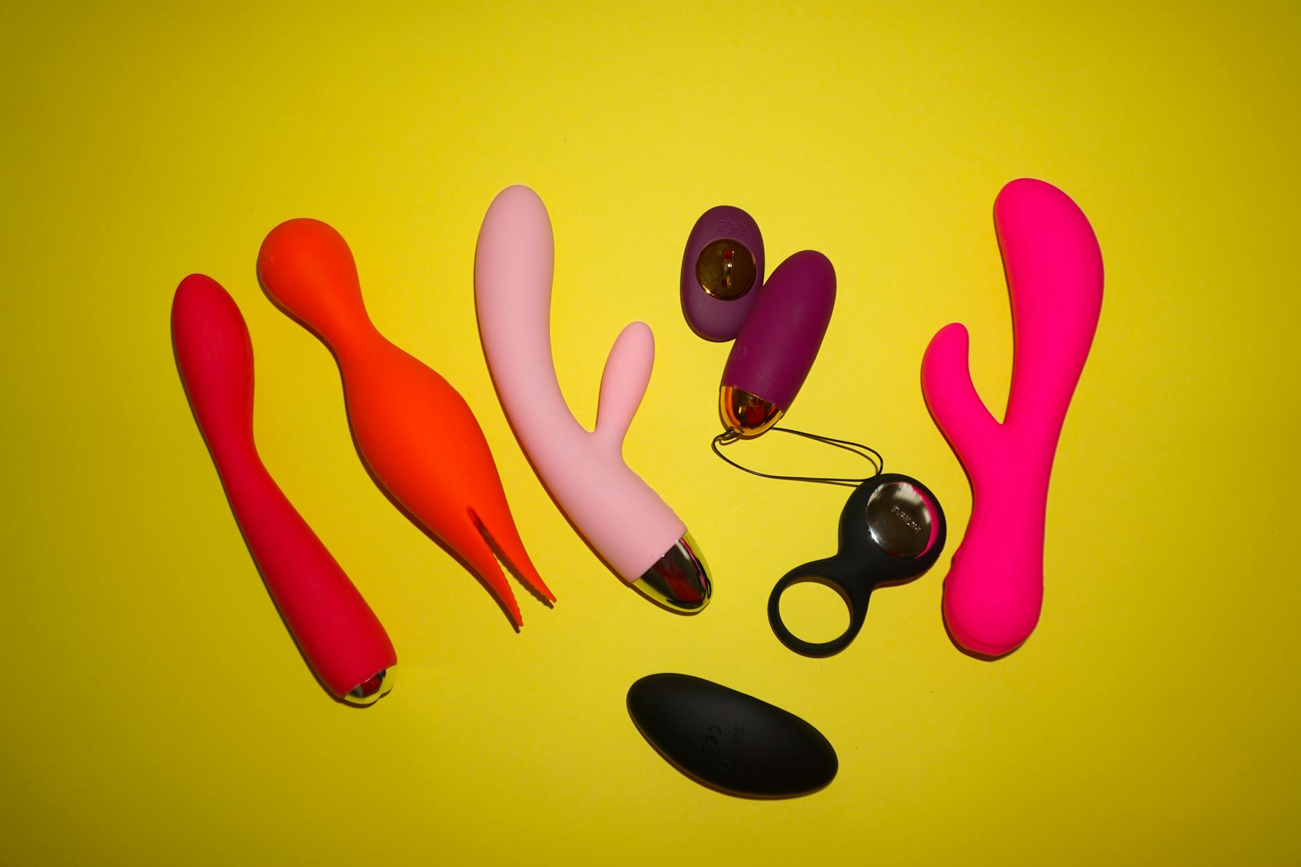 Colorful adult toys arranged on a bright yellow background, showcasing design variety